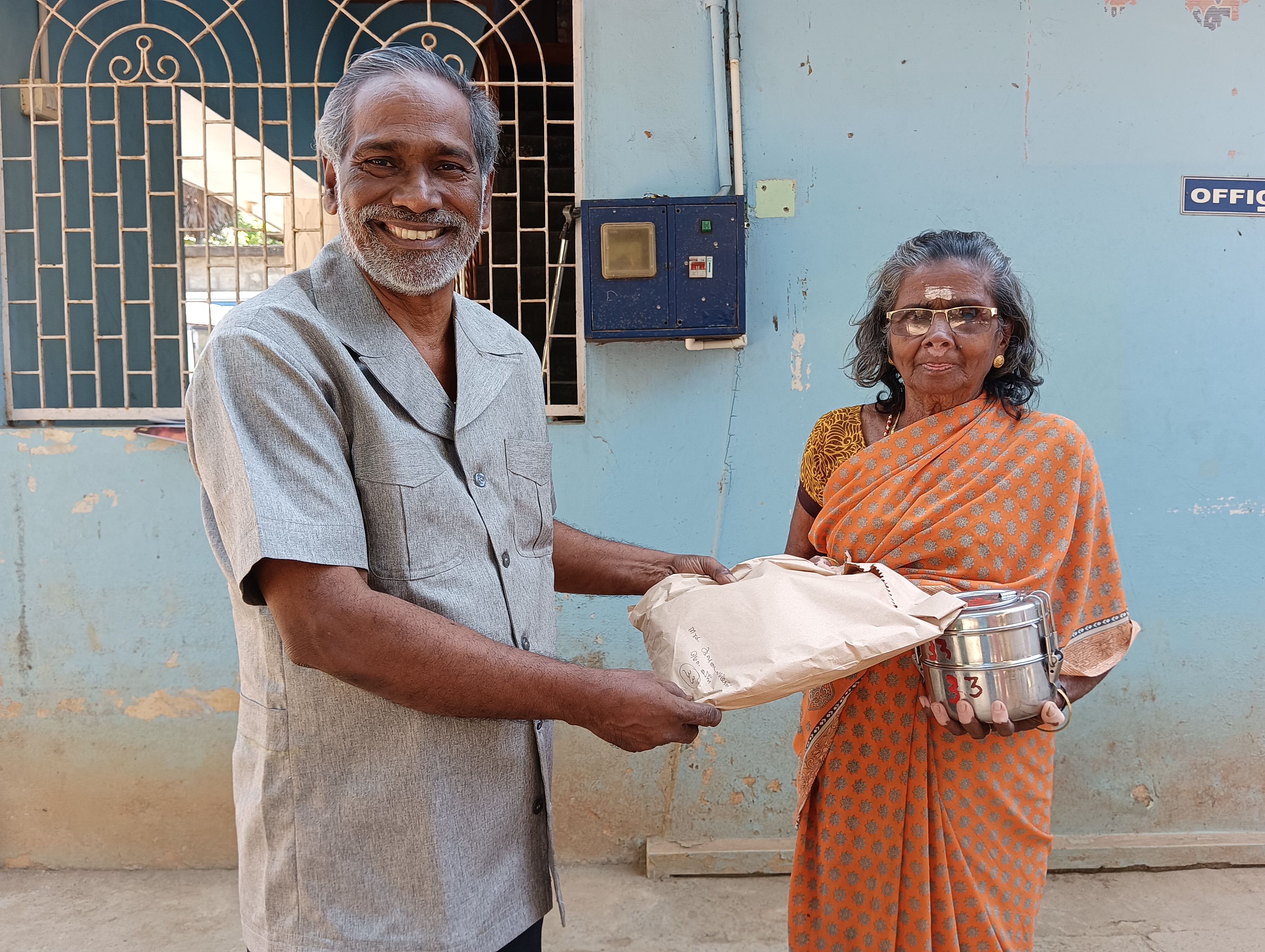 Volunteers serving hot meals to an elderly lady